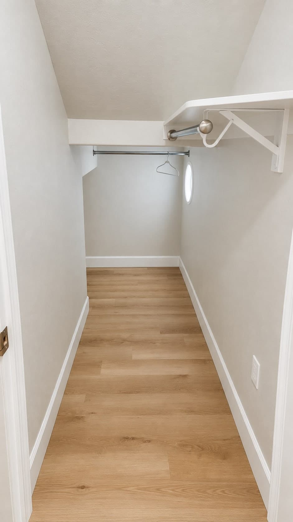 Walk-in closet with a sloped ceiling, plank flooring, a shelf with a hanging rod and a second rod at the back